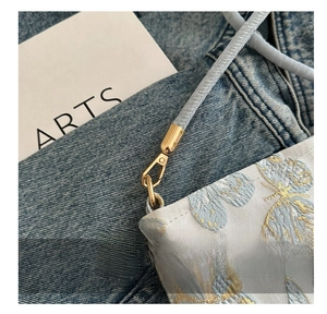 Detail of elegant butterfly embroidery on white fabric with premium gold metal hook