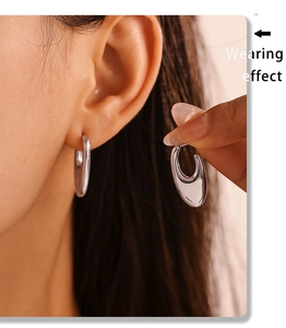 Close-up of polished silver U-shaped hoop earrings showing the elegant wearing effect