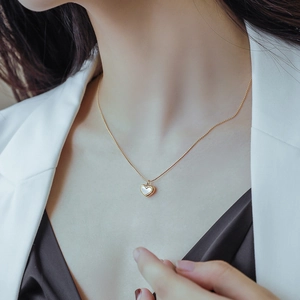 Elegant gold heart necklace with white shell inlay worn by a model in soft lighting