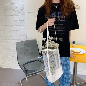 Detail of white mesh woven tote bag with daisies in a minimalist indoor lifestyle setting