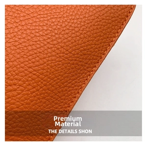 Détail du cuir grainé orange avec des coutures jaunes précises sur un sac à bandoulière