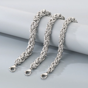 Detailaufnahme von drei Stärken der silbernen Drachenbein-Kettenarmbänder aus Titanstahl
