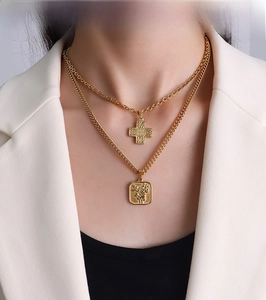 Detail of layered gold titanium necklace featuring cross and rose engraved pendants