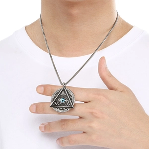 Detailed close-up of a Freemason pendant with blue eye and engraved faith inscription