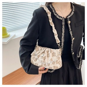 Detail of beige pleated shoulder bag with floral print and decorative flower chain strap