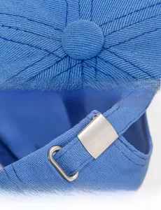 Detail of blue cotton baseball cap showing top button, stitching and adjustable metal buckle