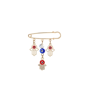 Detailed view of Hamsa Hand and Evil Eye charms on a gold tassel brooch with crystals