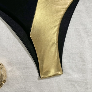 Detail of black and metallic gold patchwork fabric on sexy bikini bottom swimsuit