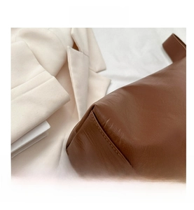 Close-up of durable brown leather base and neat stitching on a large tote bag