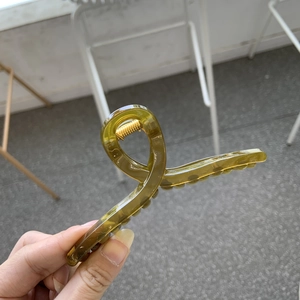 Detail of amber translucent claw clip with sturdy golden metal spring for hair styling