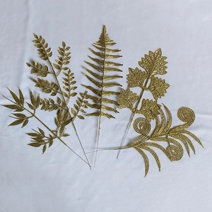 Detailed view of five distinct gold glittered artificial leaf picks for festive holiday decor