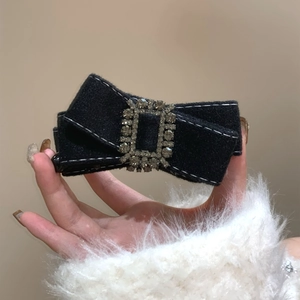 Vue détaillée d'une barrette noeud en tissu noir ornée d'une boucle rectangulaire en strass
