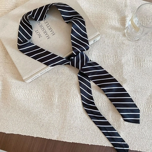 Chic black and white striped narrow silk scarf accessory styled on a vintage book