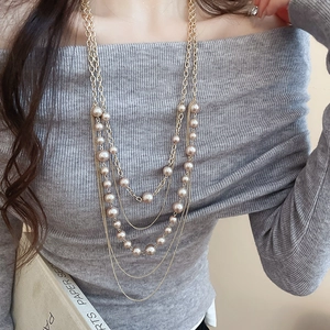 Detail of multi-layer faux pearl necklace with gold metal chain for an elegant look