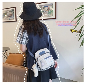 Détail du sac bandoulière beige avec fenêtre transparente et peluche d'ours