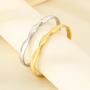 Detail of twisted wave bangles in 18K gold and silver plating on minimalist stands