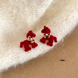 Detailed macro view of red velvet horse earrings with gold bow and pearl accent