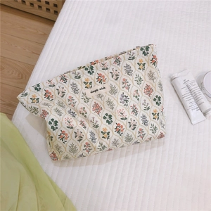 Detail of floral canvas makeup bag with small colorful flowers and woven logo tag