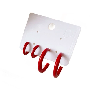 Set of four stylish red C-shaped hoop earrings displayed on a professional white card