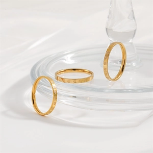 Detailed close-up of three gold-plated heart-patterned rings on a clear glass display