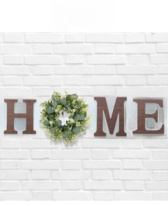 Close-up of rustic wood letters and eucalyptus wreath on white brick wall