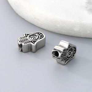 Macro shot of silver Hamsa Hand stainless steel spacer beads with detailed relief patterns
