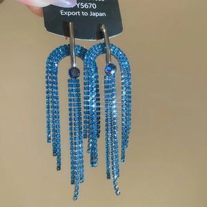 Vue détaillée de boucles d'oreilles à pompons en strass bleu avec design en demi-cercle