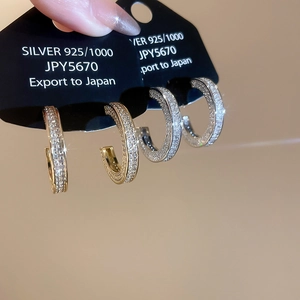 Detailed close-up of C-shaped 925 silver hoop earrings with micro-pave cubic zirconia