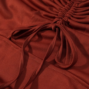 Close-up of side drawstring and ruched texture on dark red knit dress