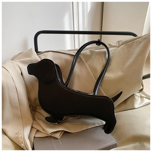 Detail view of the black leather dachshund-shaped bag resting on a beige leather seat