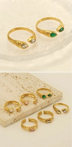 Detailed view of adjustable gold-plated rings with colorful zircon insets on textured stone