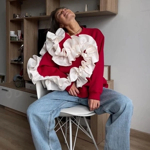 Détail d'un sweat rouge avec volants blancs sur les épaules et col rond pour femme