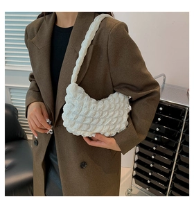 Close-up of white bubble texture fabric on a minimalist shoulder bag worn with a brown blazer