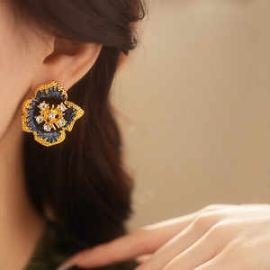 Detail of vintage flower stud earring with blue enamel and sparkling crystals on ear