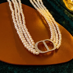 Close-up of a multi-layer faux pearl necklace featuring a sparkling crystal CD logo clasp