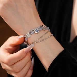 Close-up of vintage multilayer silver bracelets with blue beads and embossed charms