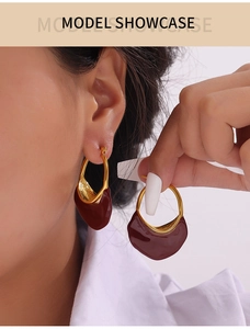Macro detail of French vintage gold hoops with red enamel pendants on model
