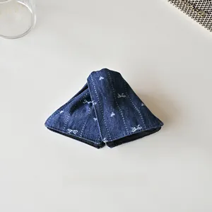Détail de la pince à cheveux en denim bleu avec motifs de nœuds blancs brodés