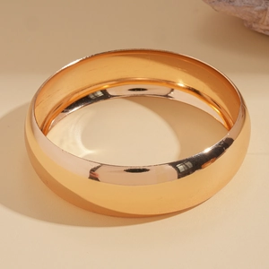 Detailed view of wide polished gold metal bangle with high-gloss mirror finish and elegant shine