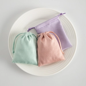 Detailed view of mint, pink and purple drawstring jewelry pouches on a ceramic tray