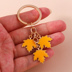 Handheld view of golden ginkgo leaf keychain with yellow enamel pendants on a ring