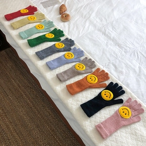 Primer plano de guantes de punto en degradé con parche amarillo de cara sonriente