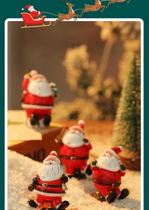 Miniature resin Santa Claus figurines in a snowy Christmas scene with bokeh lighting