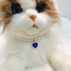 Detail of white faux pearl cat collar with a blue heart crystal pendant on a ragdoll cat