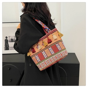 Ethnic canvas tote bag with geometric patterns and colorful tassels worn by a model