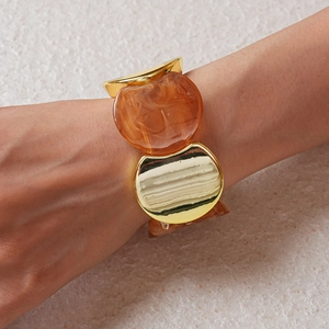 Dettaglio del bracciale elastico largo con metallo dorato e resina ambrata