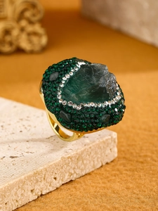 Macro shot of an irregular green raw crystal ring with sparkling gold metal setting