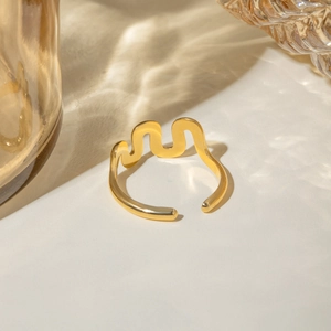 Detailed view of gold wave-shaped titanium steel bangle reflecting artistic water shadows