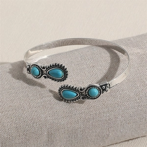 Detailed close-up of retro silver bangle with turquoise teardrop and circular stone inlay