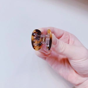 Macro view of a mini tortoiseshell hair claw clip with acetate finish and metal spring